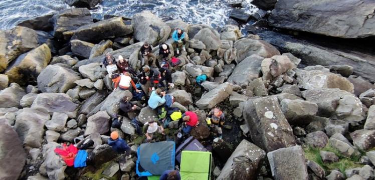 Queen's mountaineering club sitting on boulders